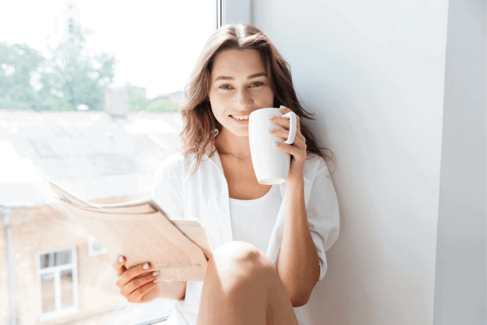 woman drinking coffee reading paper